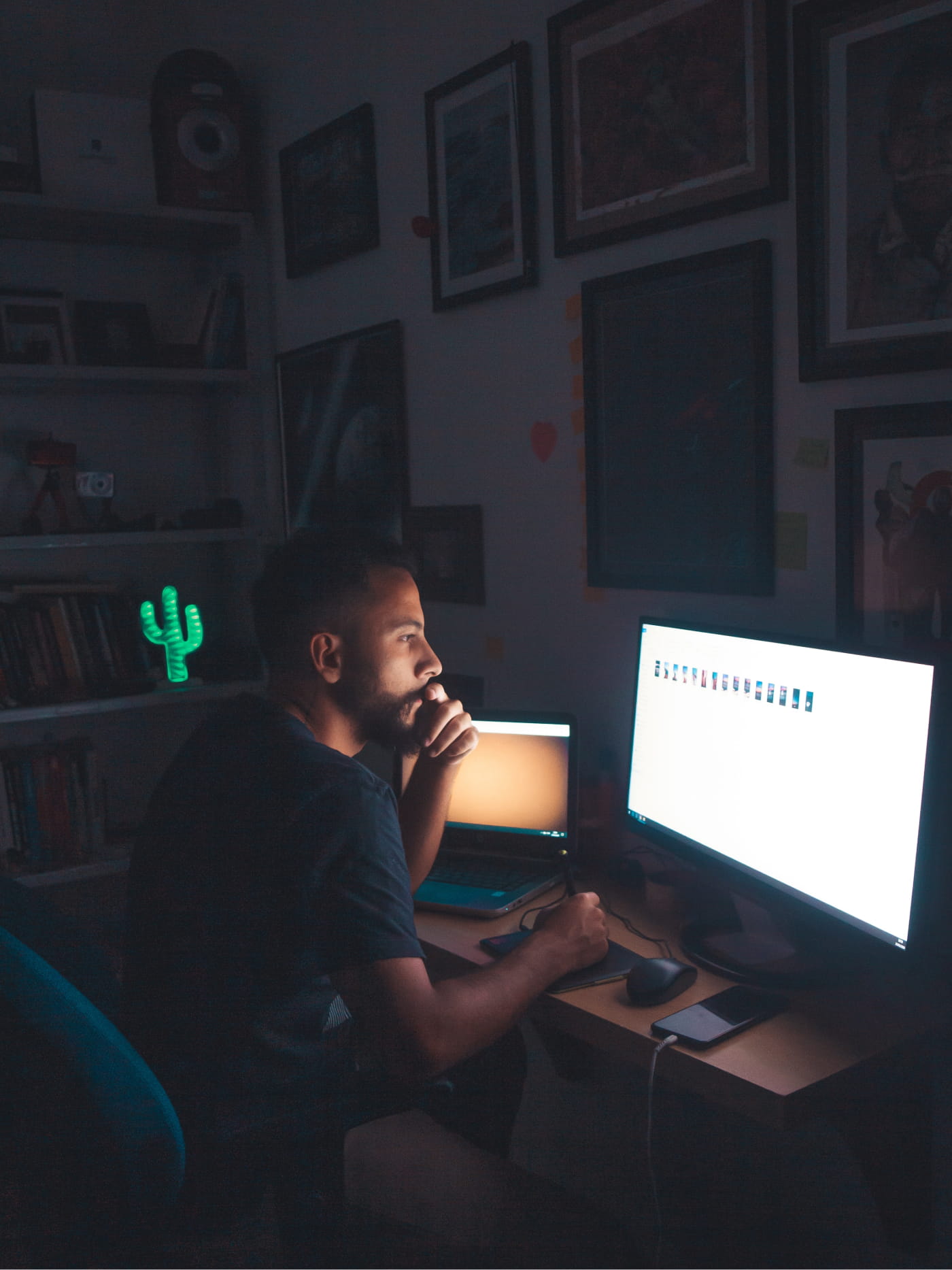 A person sitting in the dark in front of a screen looking at images.