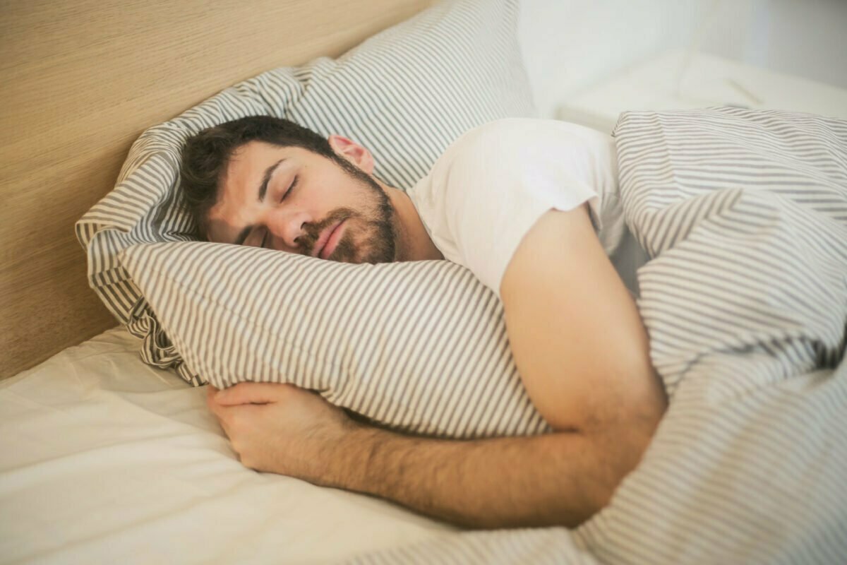 a person in a white shirt sleeping in bed